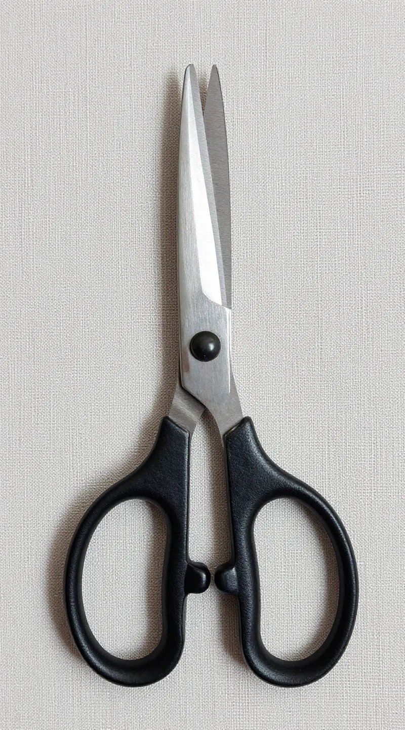 sharp stainless steel fabric scissors on linen mat, overhead shot